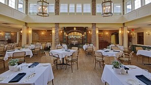 A spacious dining area with multiple tables and chairs, a brick fireplace, and large windows. - The Briars Resort & Spa (Georgina)