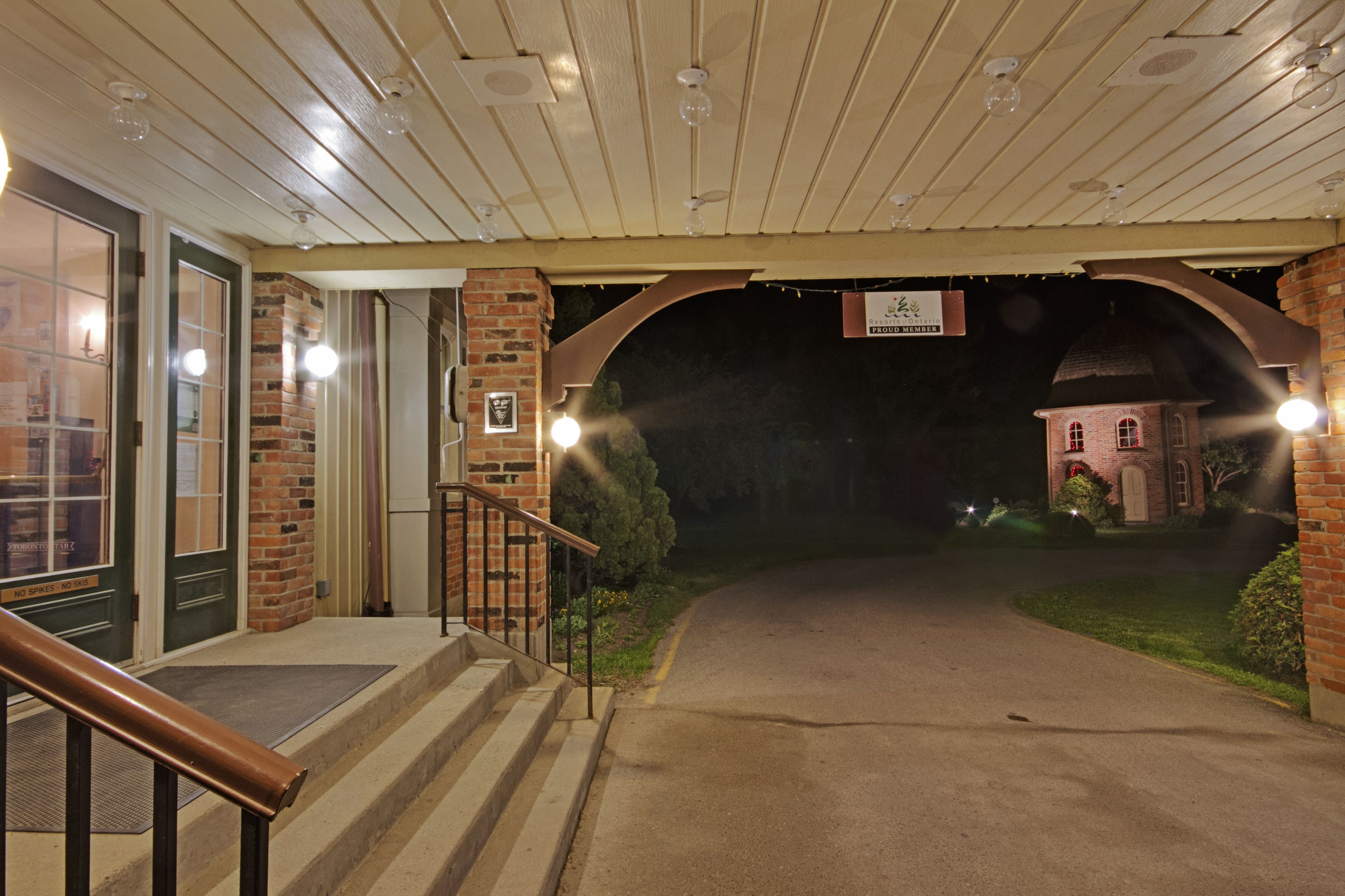 A building entrance with a brick facade, a wooden porch, and a sign indicating membership.
