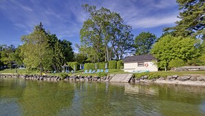 A lakeside view with a gazebo, lounge chairs, and a small building with a lifebuoy. - The Briars Resort & Spa (Georgina)
