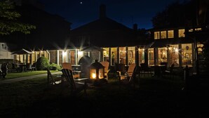 An outdoor seating area with chairs and tables, a fire feature, and a building with large windows. - The Briars Resort & Spa (Georgina)