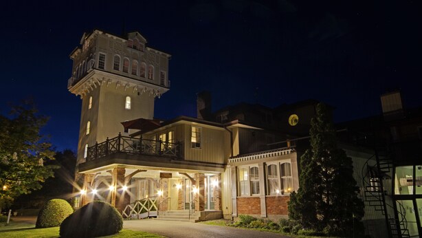 A large, historic building with a prominent tower, a covered porch, and a well-lit entrance. - The Briars Resort & Spa (Georgina)