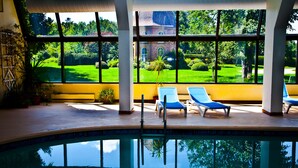 A pool area with lounge chairs and a view of a green landscape through large windows. - The Briars Resort & Spa (Georgina)