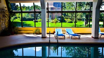 Una piscina techada, sombrillas, sillones reclinables de piscina