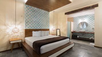 A modern bedroom with a large bed, bedside lamps, and a bathroom with a sink and mirror.