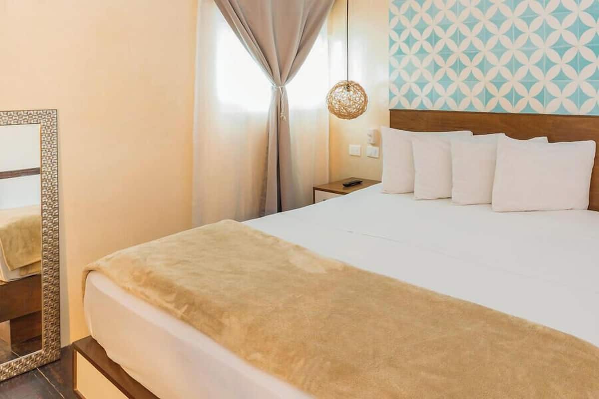 Een hotelkamer met een bed, een nachtkastje, een lamp en een behangen muur.