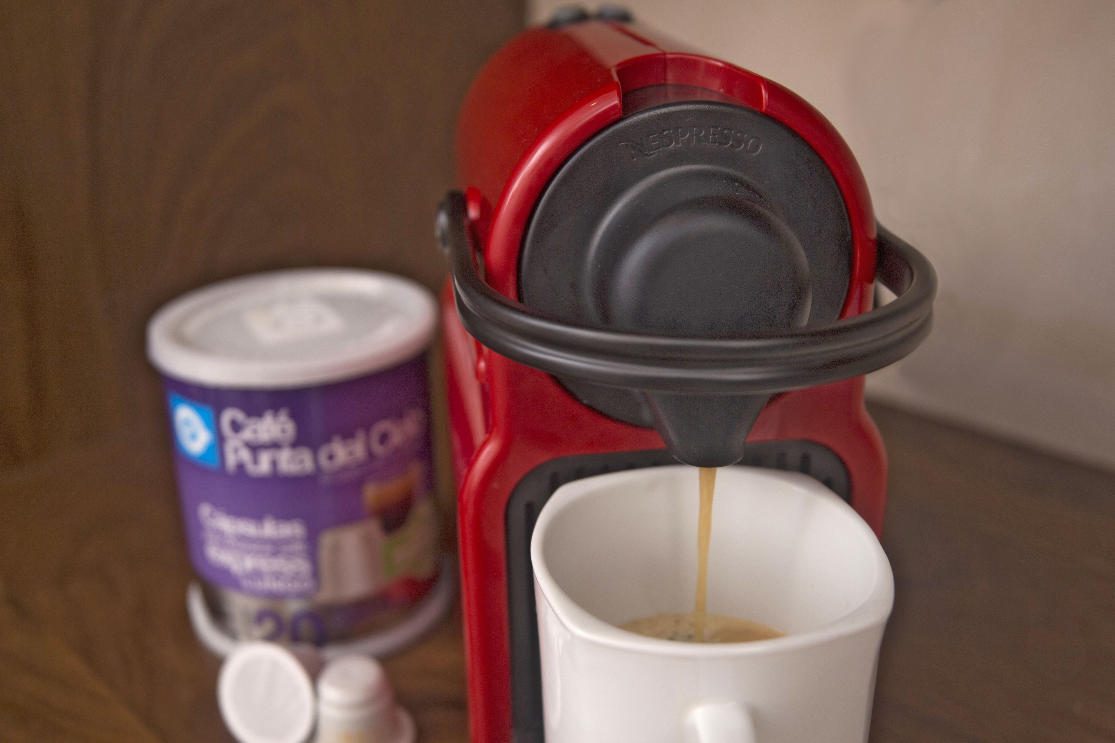 Una máquina de espresso roja sirviendo café en una taza blanca.