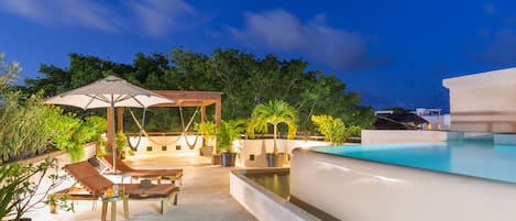 Una piscina al aire libre, sillones reclinables de piscina