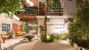 An indoor garden with a seating area, a decorative tree, and a wall with a quote.