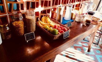 Una encimera de madera con botes de cereales, una cesta de frutas y un letrero que dice 'Buenos Días'.