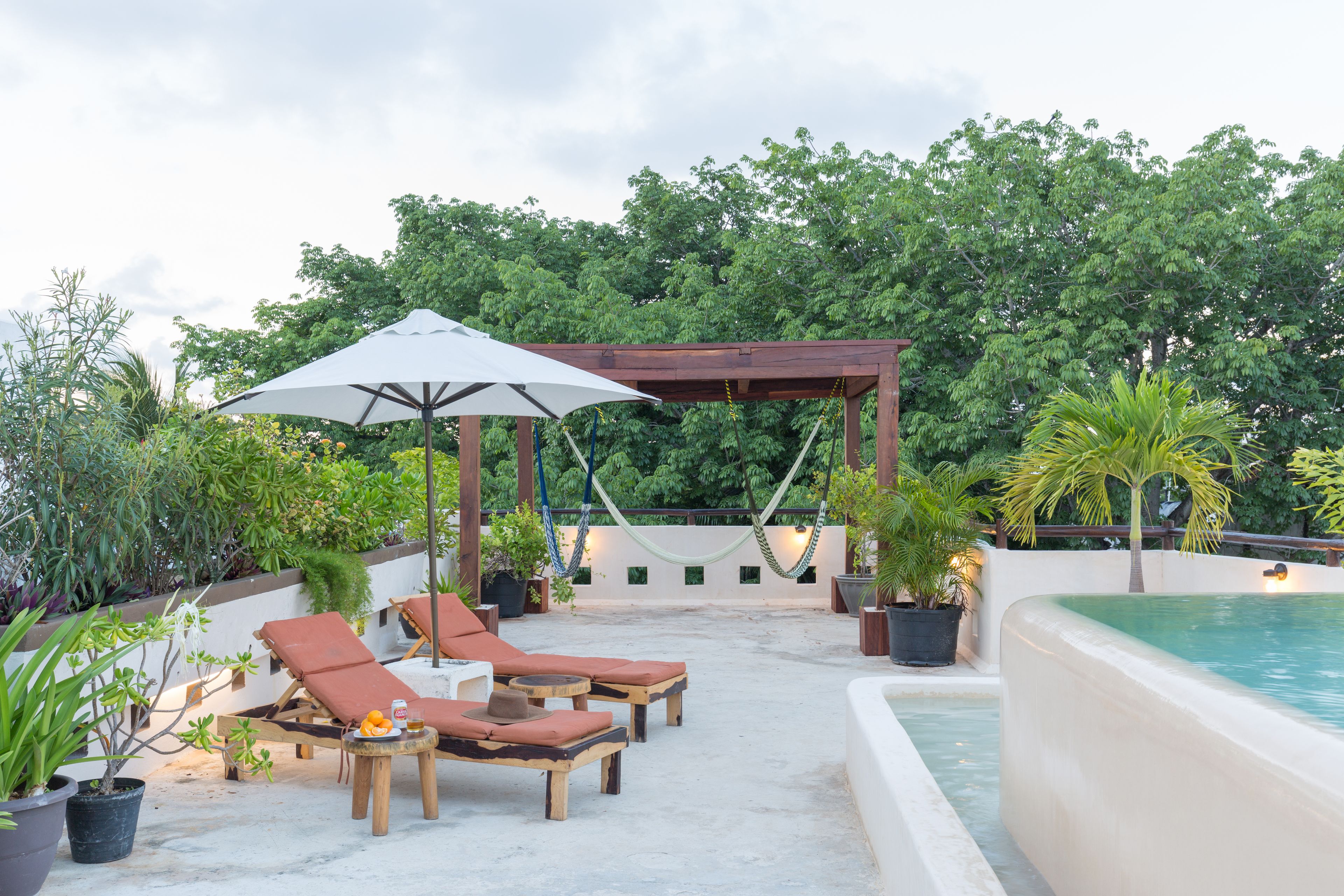 Terraza en la azotea con sillones de descanso, una hamaca y una piscina.