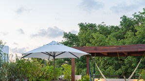 A poolside area with lounge chairs, a covered seating area, and a hammock.