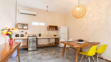 A compact kitchen with a stove, sink, and refrigerator. There is a dining table with chairs and a vase of flowers.