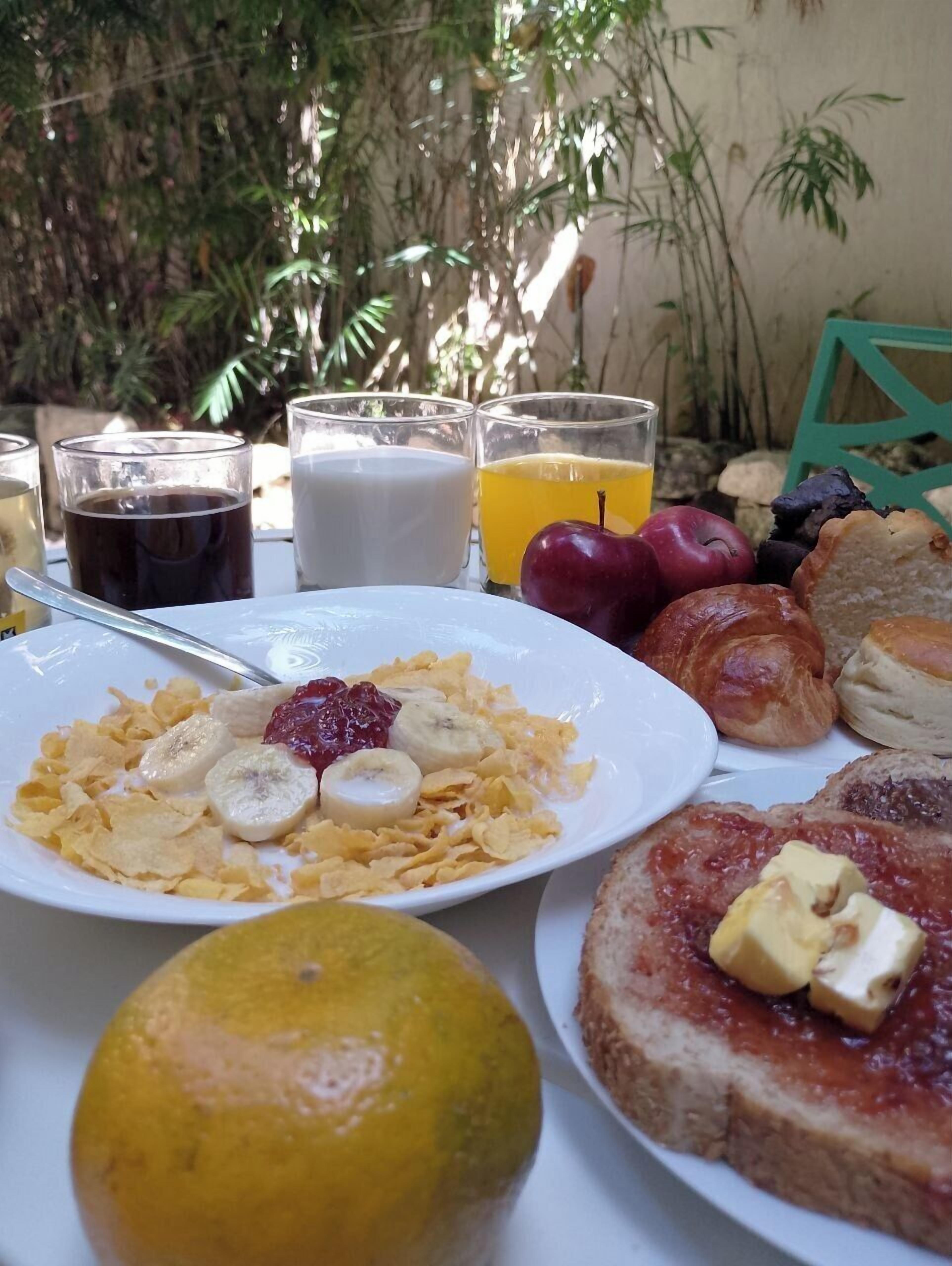 A breakfast table with cereal, fruits, pastries, and drinks.