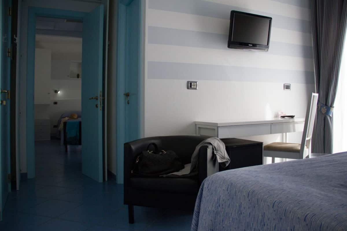 A hotel room with a bed, a desk, a television, and a chair.
