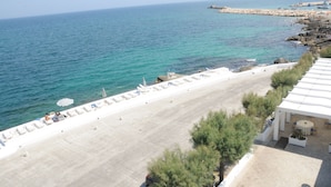 A beachside hotel with a terrace, lounge chairs, and umbrellas. - Hotel La Sorgente (Fasano)