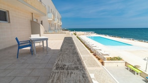A poolside area with a view of the sea, a table, and a chair. - Hotel La Sorgente (Fasano)
