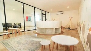 Een modern interieur met een ronde centrale tafel, kleine ronde tafels en een groot vloerkleed.