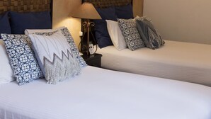 Ein Hotelzimmer mit zwei Betten, einem Nachttisch mit Lampe und einer strukturierten Wand.