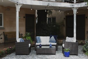 Un espacio al aire libre con mobiliario de mimbre, un sofá blanco y una mesa de centro.