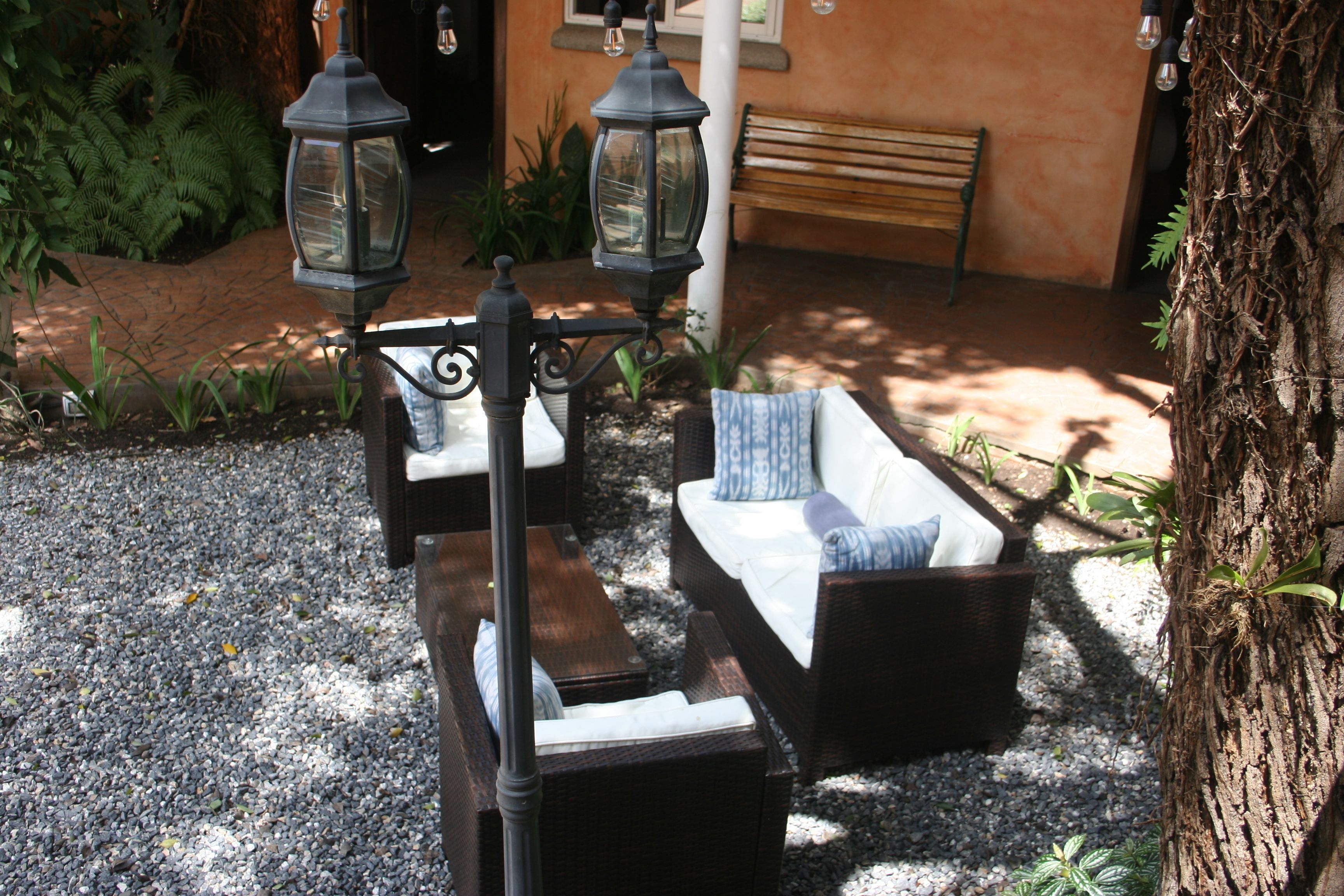 A garden area with a bench, a wicker sofa, and two lanterns.