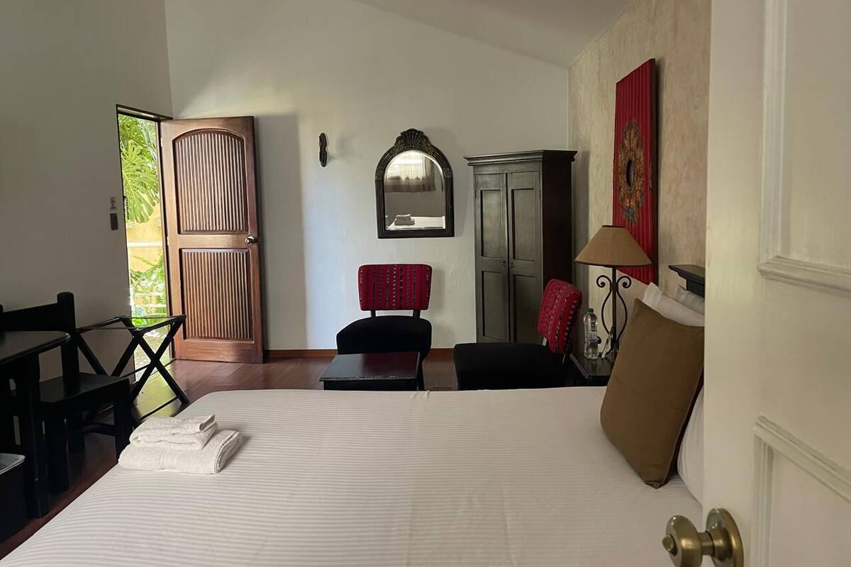 Een hotelkamer met een bed, een bureau, een stoel, een kledingkast en een deur naar een balkon.