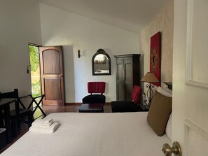 A hotel room with a bed, a desk, a chair, a wardrobe, and a door leading to a balcony. - Hotel Ciudad Vieja (Guatemala City)