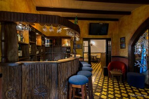 A bar area with wooden bar counters, stools, and hanging light fixtures.
