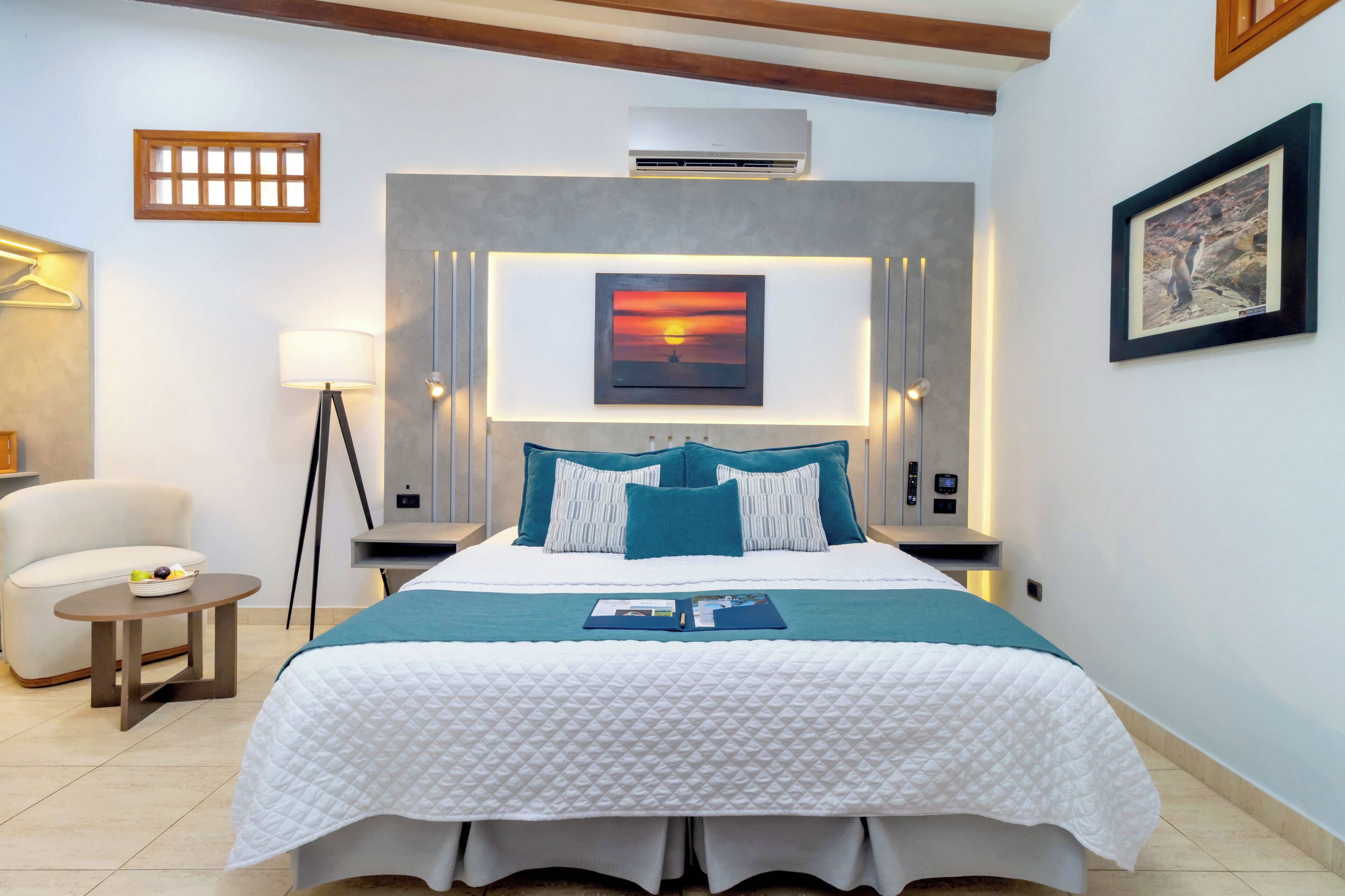 Ein Hotelzimmer mit einem Bett, einem Nachttisch mit Lampe, einem Sessel und einem Bild an der Wand.