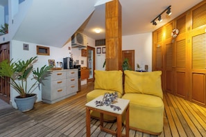 Un interior moderno con suelo de madera, un sofá amarillo, una mesita y una planta en maceta.
