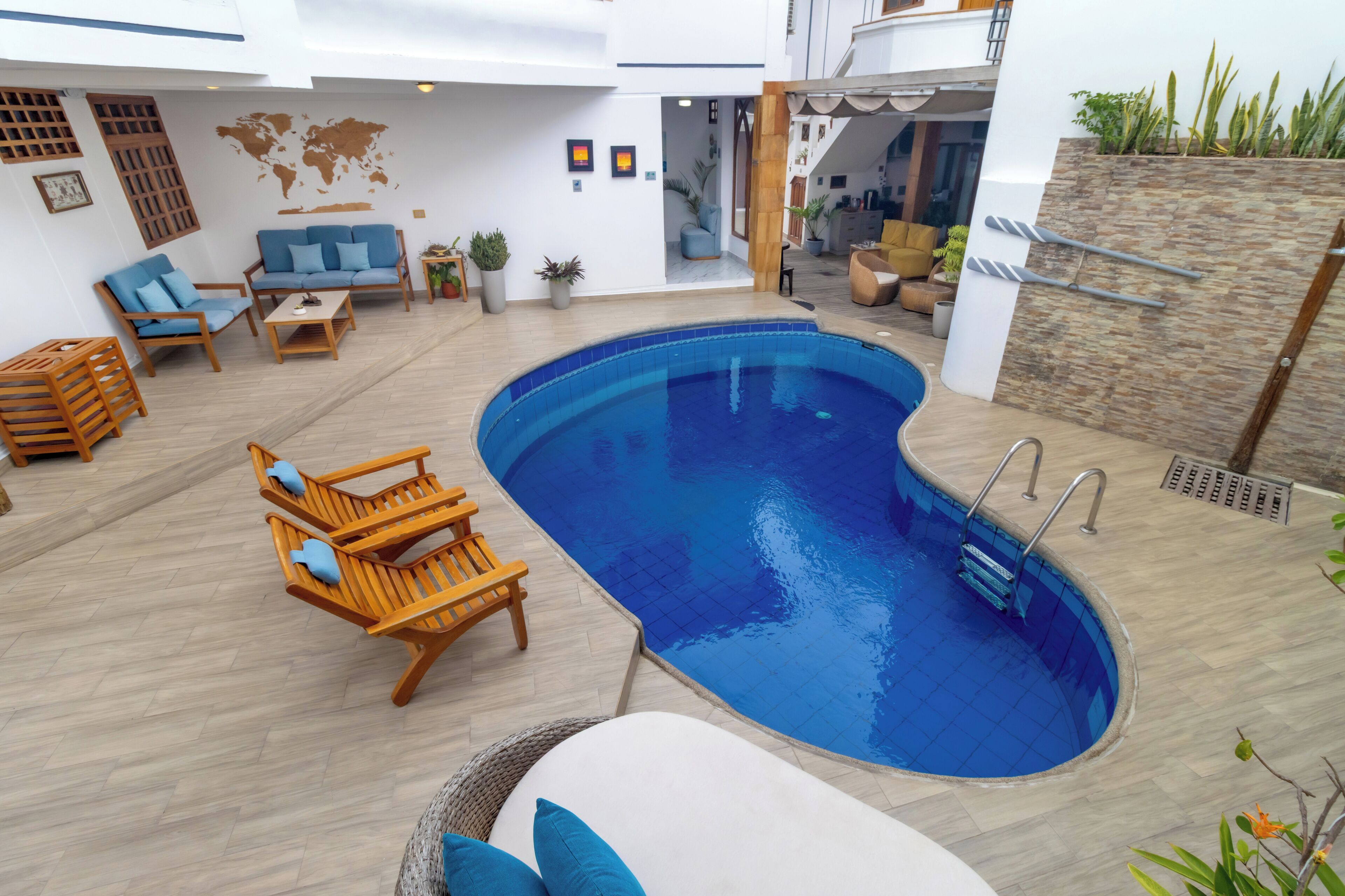 A modern indoor pool area with wooden furniture, a blue pool, and a stone accent wall.