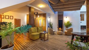 A cozy outdoor seating area with wooden flooring, a sofa, a table, and potted plants. - Hotel Santa Fe (Puerto Ayora)