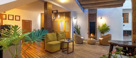 Una zona de estar al aire libre acogedora con suelo de madera, un sofá, una mesa y plantas en macetas.