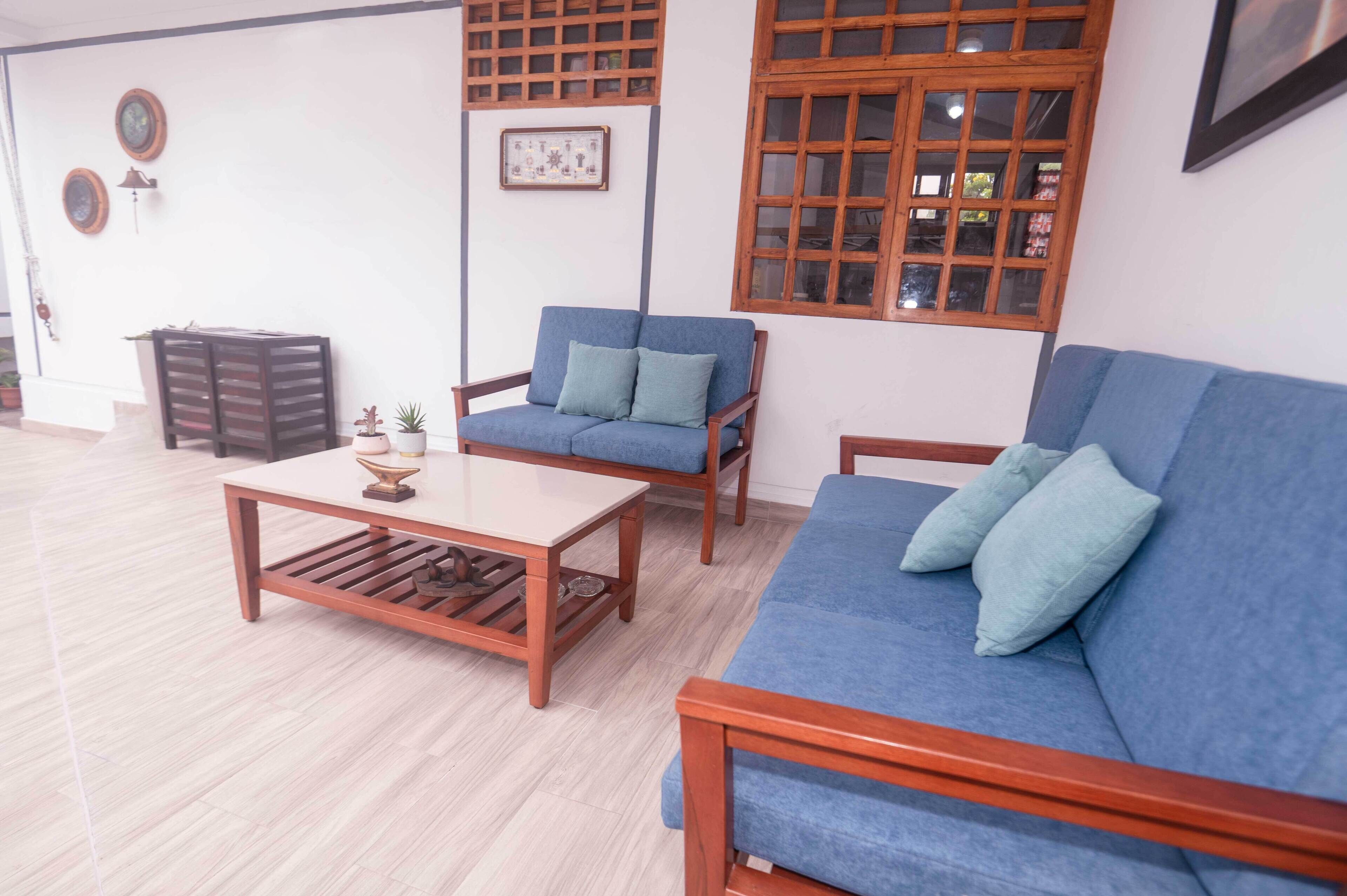 Una sala de estar con un sofá azul, una mesa de centro de madera y un sillón azul.