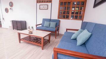 Una sala de estar con un sofá azul, una mesa de centro de madera y un sillón azul.