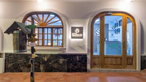 A hotel lobby with a stone wall, wooden door, and a sign for Hotel Santa Fe. - Hotel Santa Fe (Puerto Ayora)