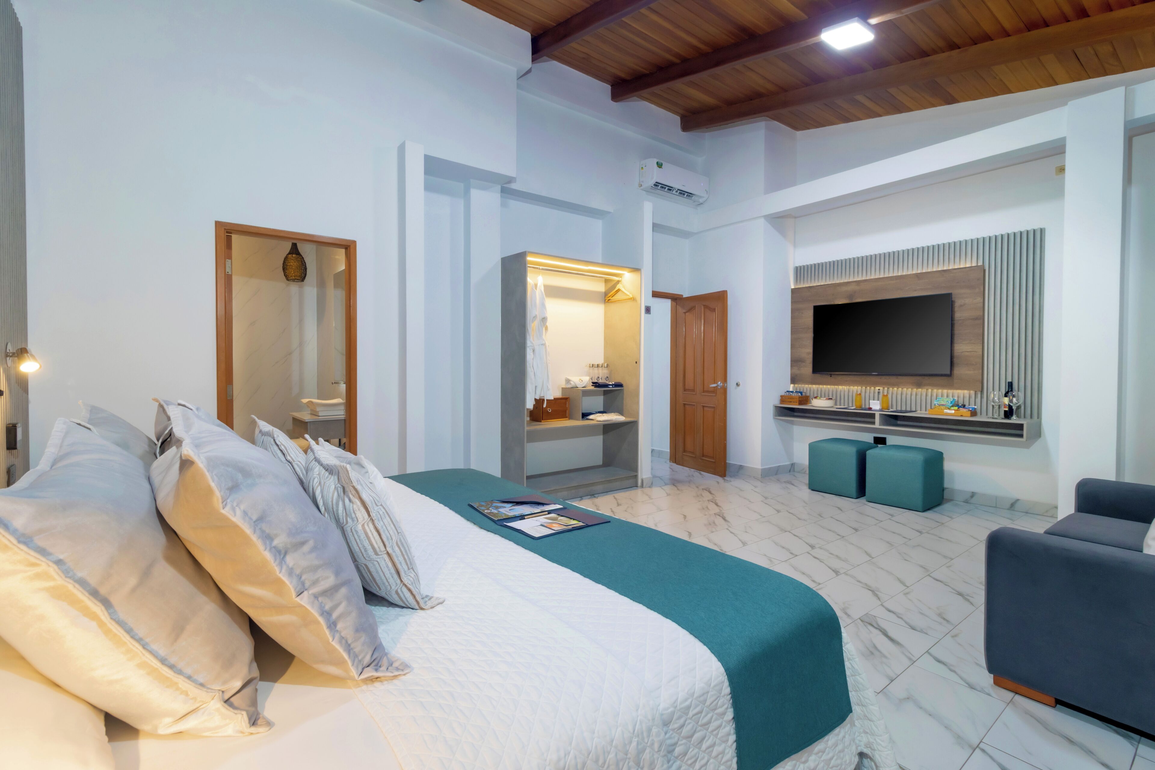 A bedroom with a bed, a TV, a wardrobe, and a seating area.