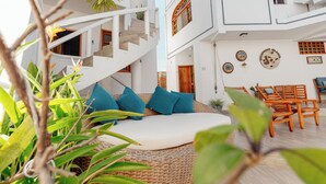 A modern interior with a white staircase, a round seating area with blue cushions, and wooden furniture. - Hotel Santa Fe (Puerto Ayora)