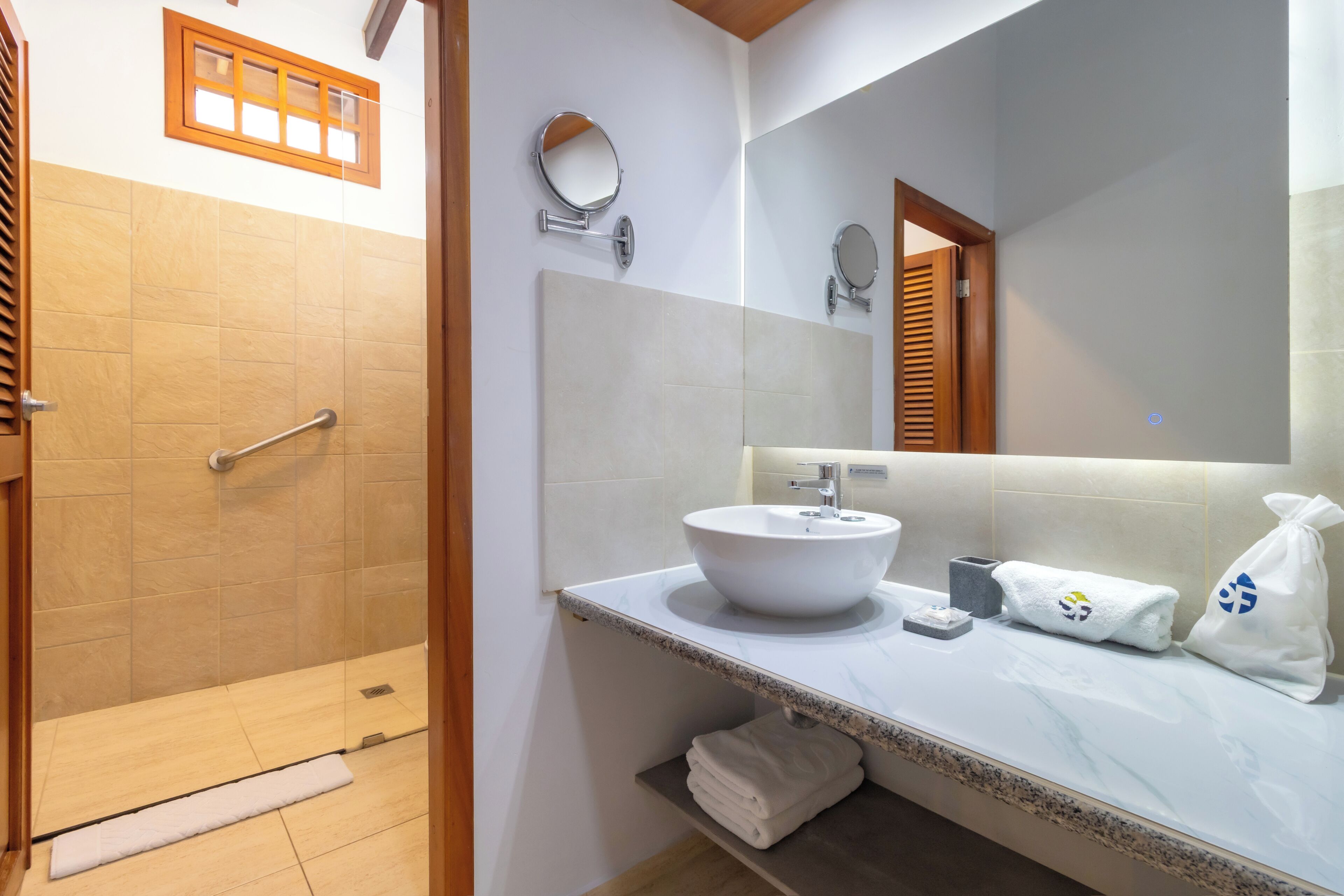 A bathroom with a shower, a sink, a mirror, and a towel rack.
