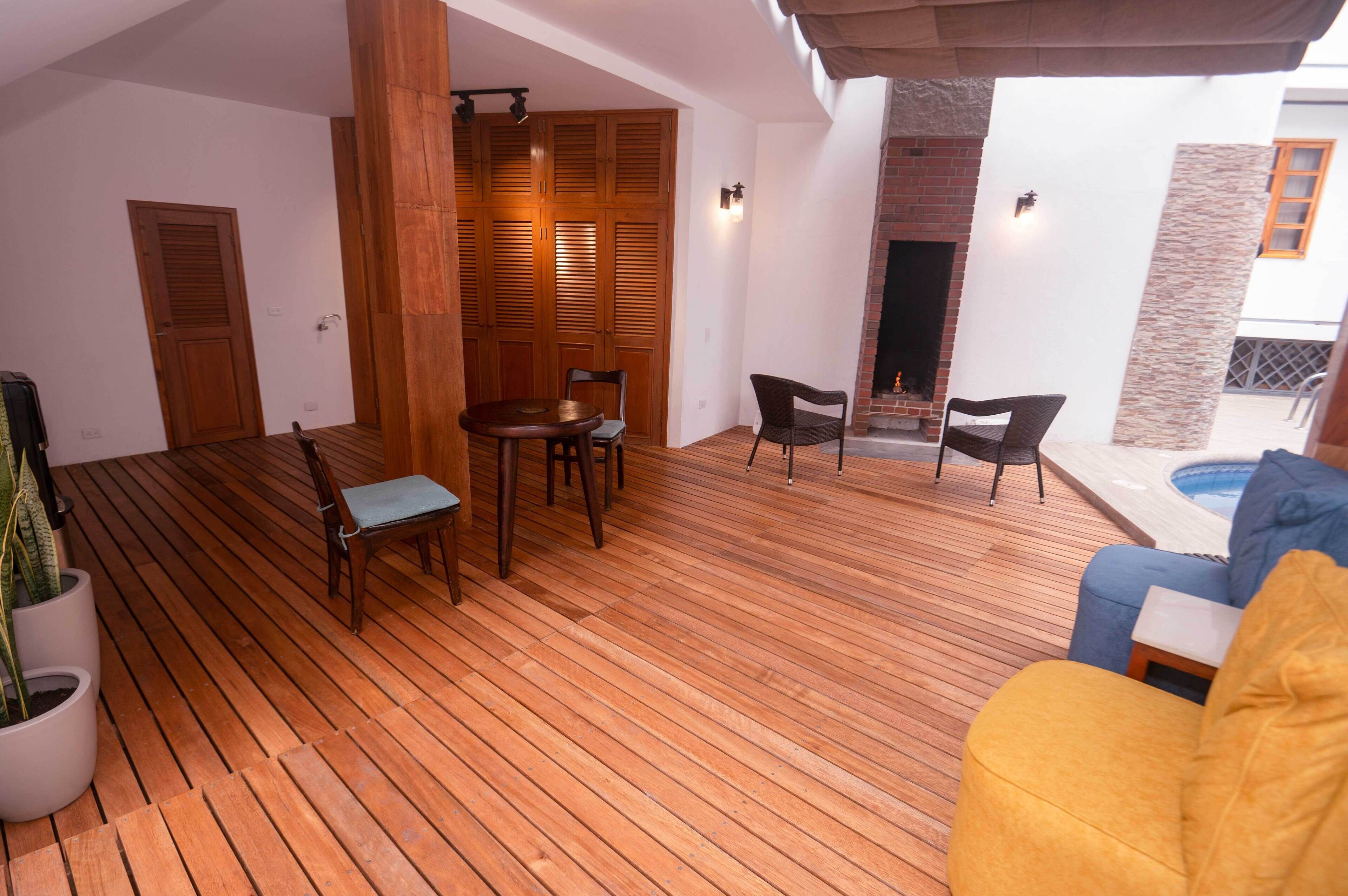 A wooden deck with a dining table and chairs, a sofa, and a potted plant.