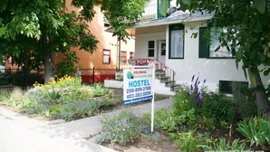 A hostel with a signboard displaying contact information and a website URL.