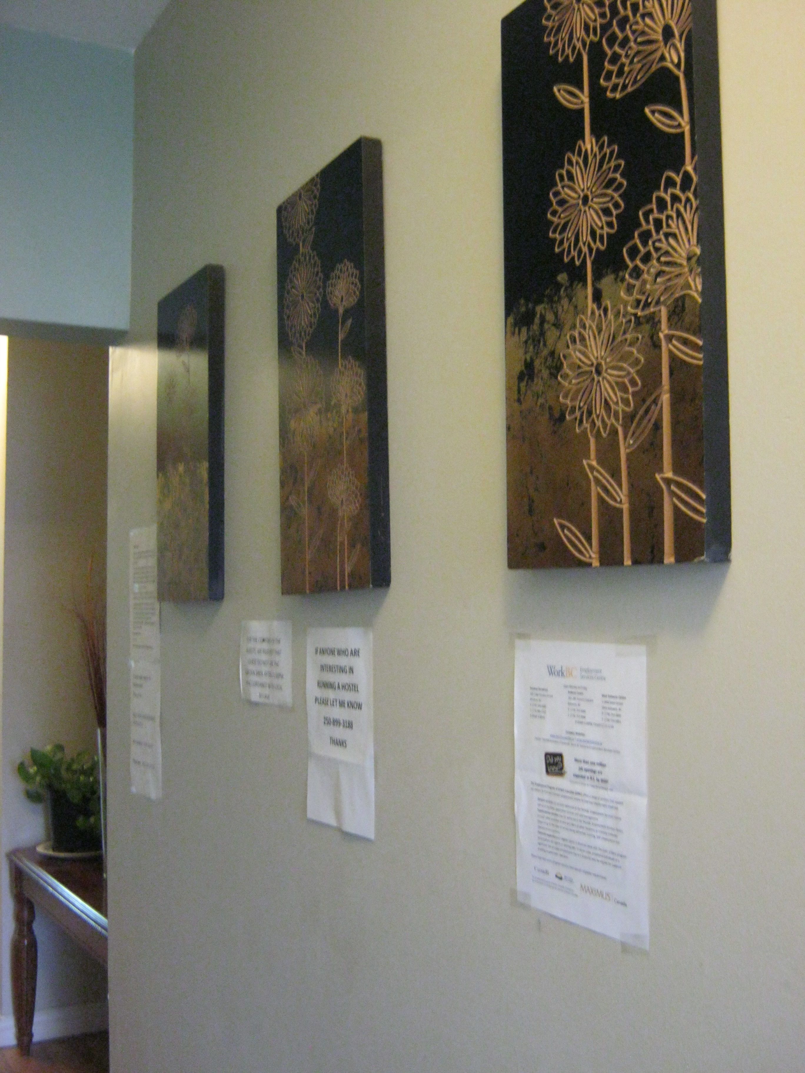 Artwork on a wall, a sign with contact information, and a small plant.