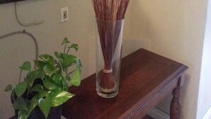 A wooden table with a vase of dried plants and a potted plant on it.