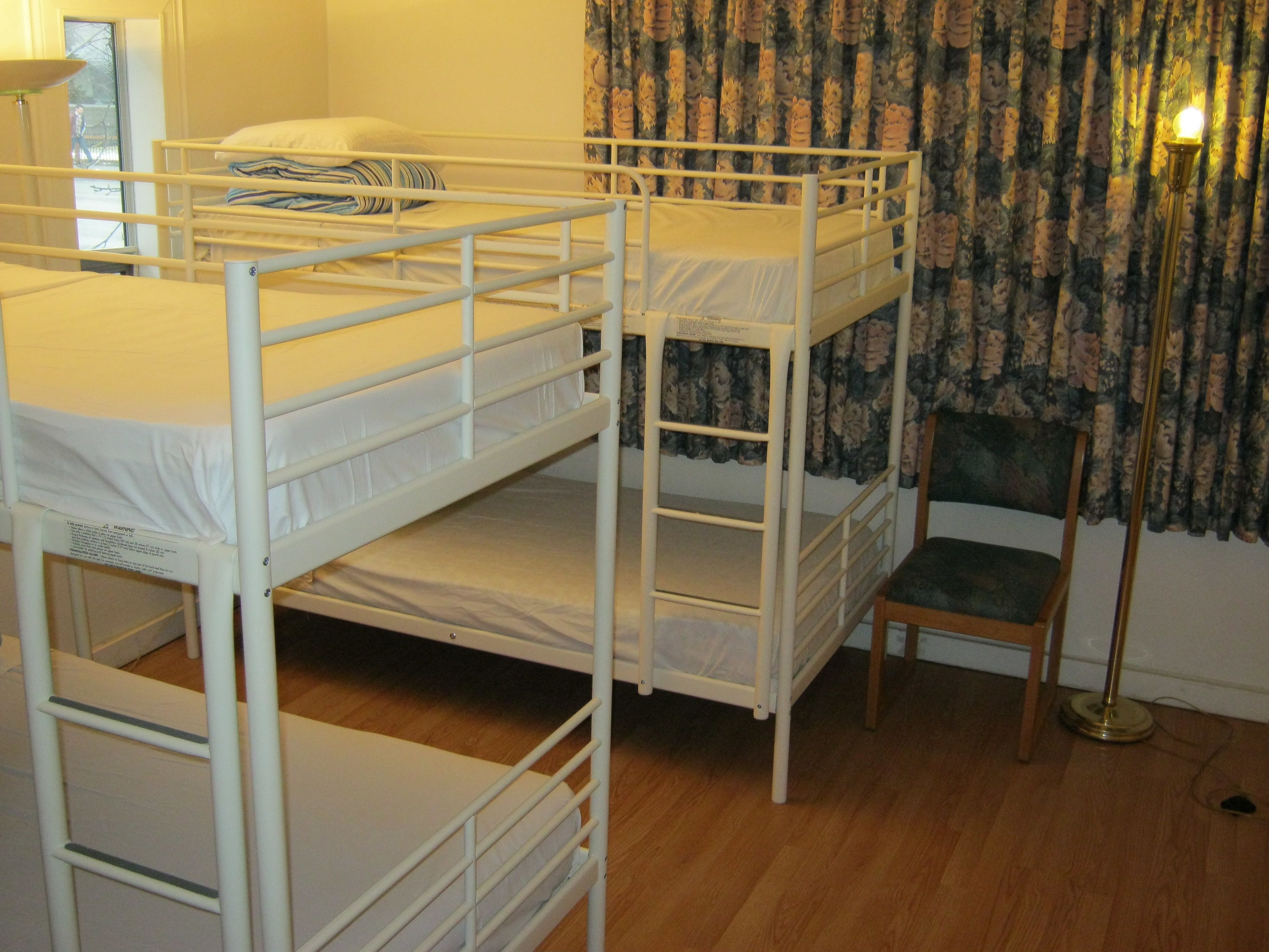 Habitación con literas, una silla y una lámpara.