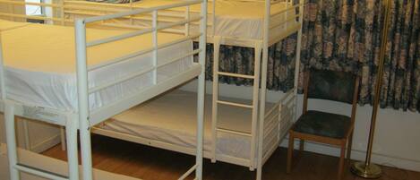 Habitación con literas, una silla y una lámpara.