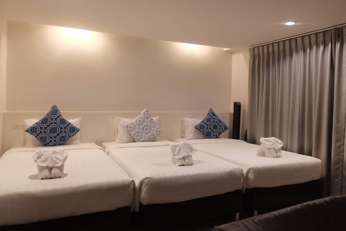 Une chambre d’hôtel avec deux lits, chacun recouvert d’une courtepointe blanche et agrémenté d’un coussin à motifs bleus. Deux serviettes blanches sont posées sur les lits.