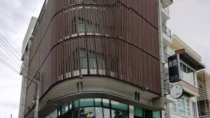 Een modern gebouw met een gebogen gevel, grote ramen en een bord dat wijst op een bedrijf of kantoorruimte.