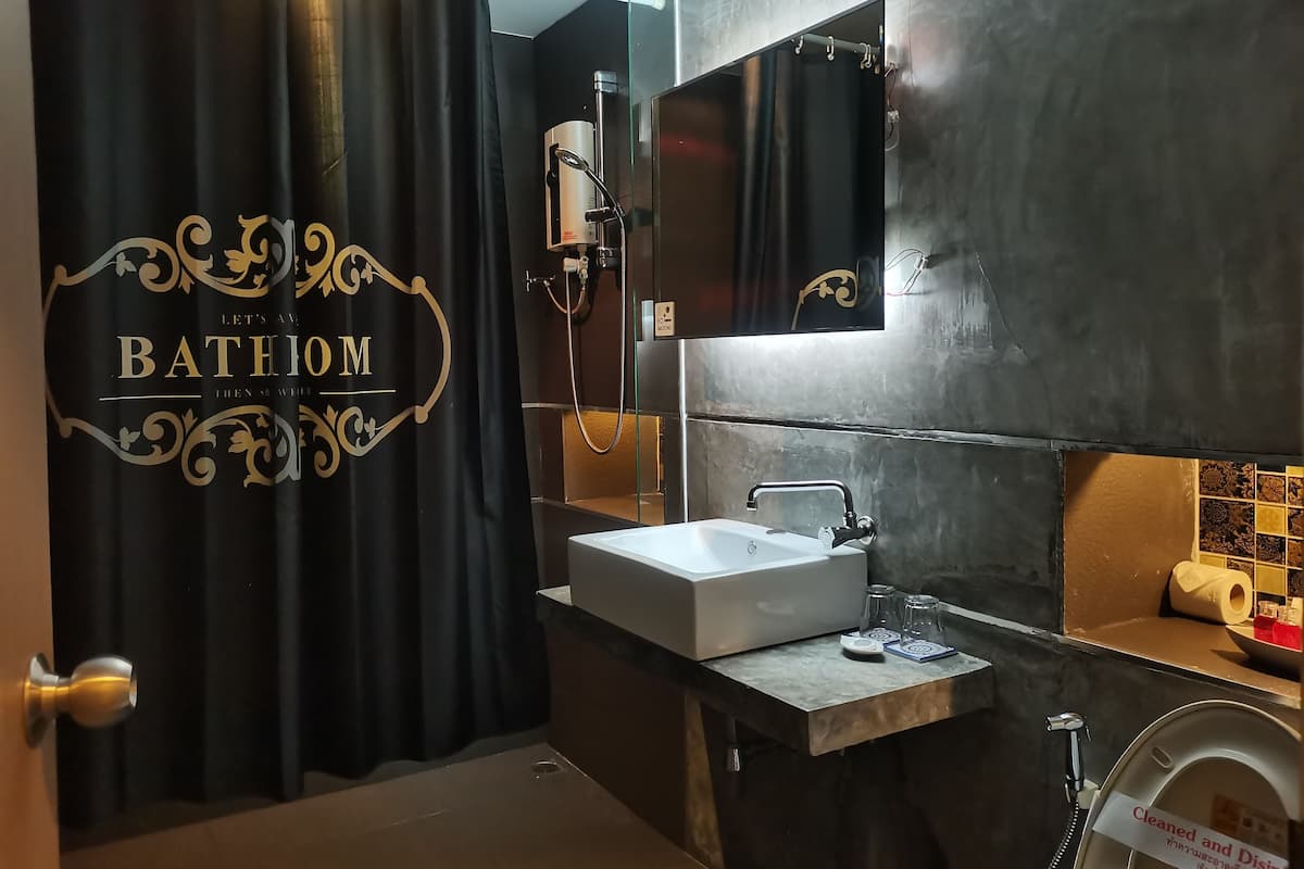 Une salle de bain avec un rideau de douche noir, un lavabo blanc et un miroir au-dessus.