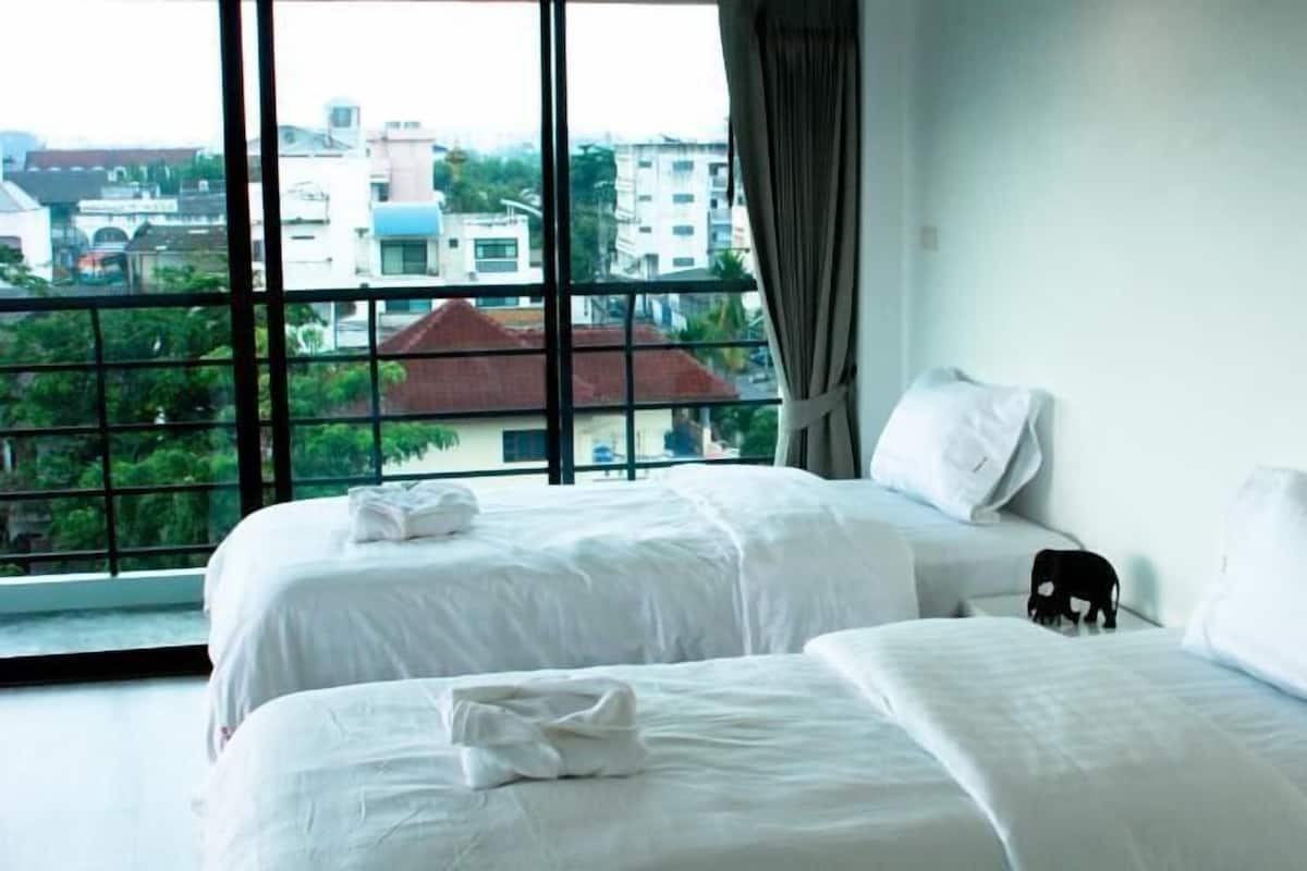 Une chambre d’hôtel avec deux lits, une grande fenêtre et une vue sur les immeubles.