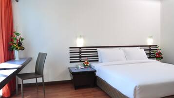 Una habitación de hotel con una cama, un escritorio, una silla, una mesita de noche y dos lámparas de pared.