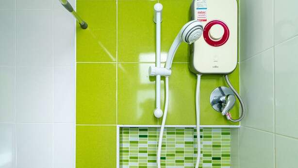 Une salle de bain équipée d’une douche, d’un pommeau de douche à main et d’un robinet mural.